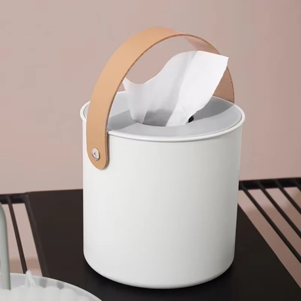 Round white tissue box holder with a decorative brown synthetic Leather carrying Handle.
